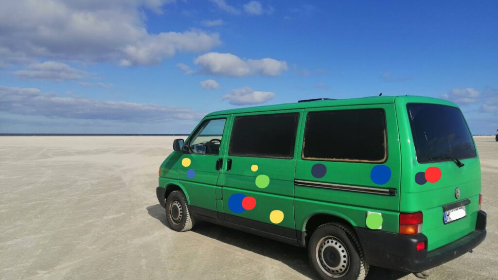 Der Konfettibus am Strand bei blauem Himmel und ein paar Wolken