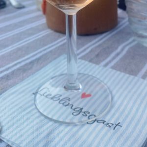 Glas auf Serviette mit Aufdruck "Lieblingsgast"