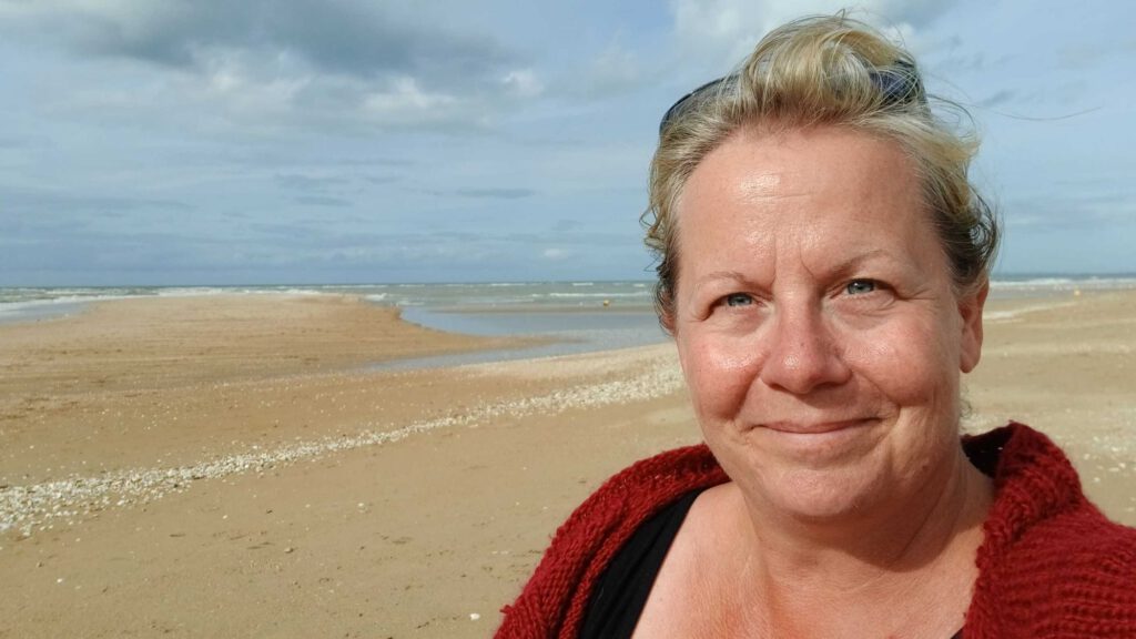 Glücklich in Frankreich - Anja entspannt im Urlaub am Meer in die Kamera grinsend